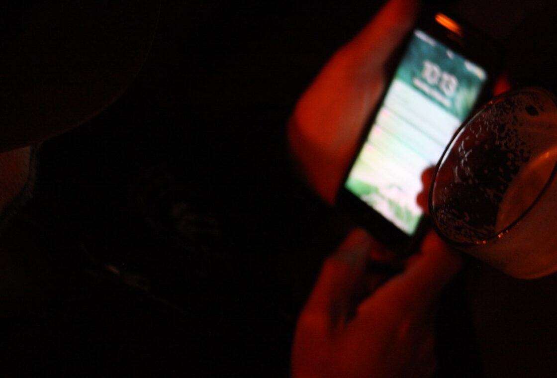 A hand holding a glowing phone in a dark room
